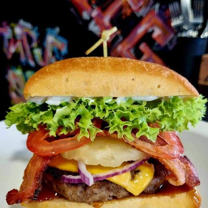 A loaded burger with bacon, pineapple and red onion